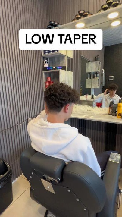 A low taper cut into curly hair