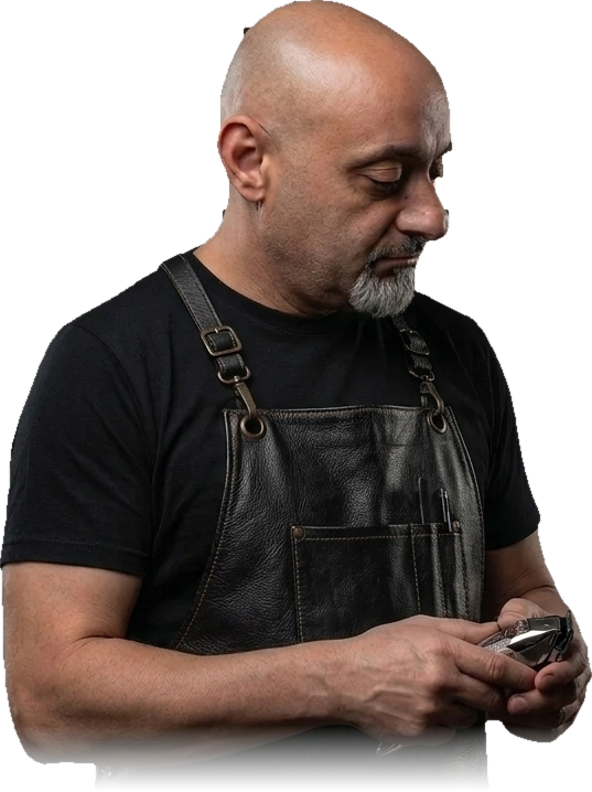 Mario, the barber at Magic Touch, in a leather apron holding clippers